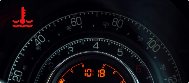 A close-up of a car's dashboard with an illuminated coolant light.