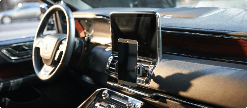 Vehicle interior with an in-dash screen and phone mounted to the dashboard. 