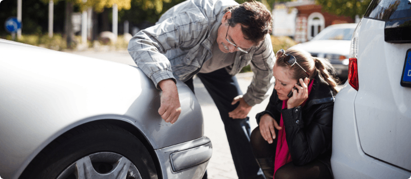 Two people evaluating the damages after a minor car accident.