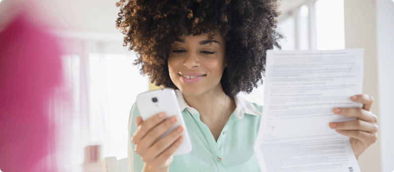 Happy person holding a document while dialing her phone.