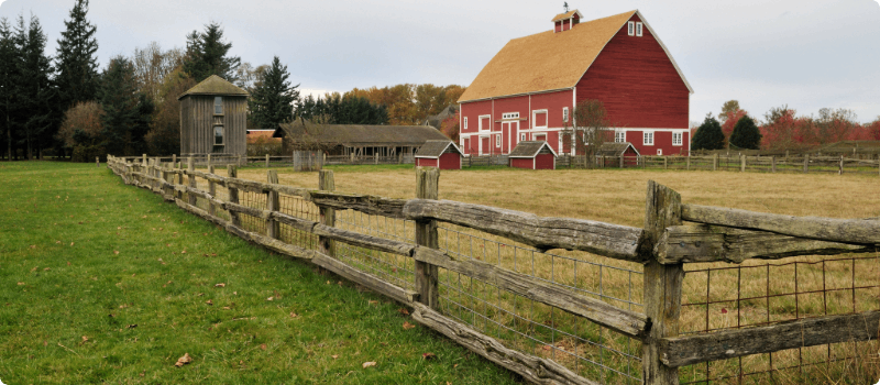 A farm with a large barn and fence.