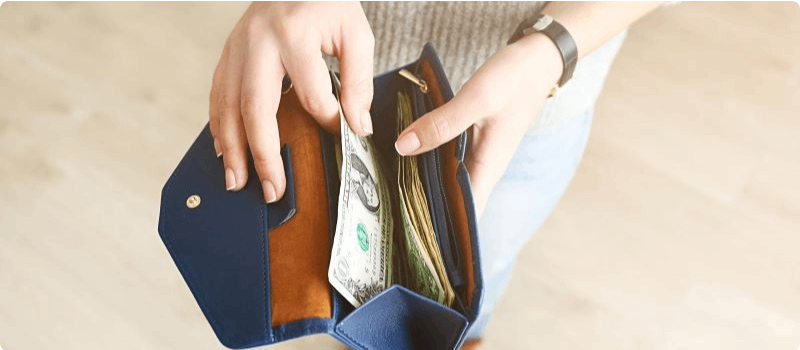 Woman removing cash from her open wallet. 