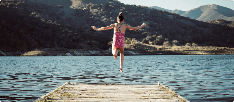 Little girl jumping off a dock on a sunny day. 