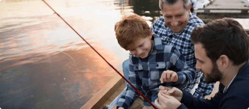 Grandfather, father and son fishing on a dock. 