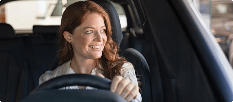 Smiling person driving a vehicle. 