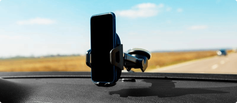 Phone resting in a car mount attached to a windshield. 