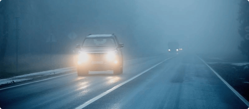 Cars driving on a foggy road.