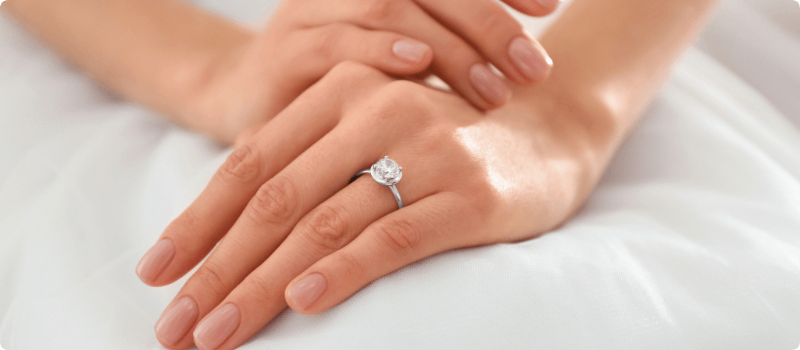 A bride's hands displayed in a way that highlights her wedding ring.