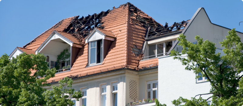 A close-up of a home with a fire-damaged roof.