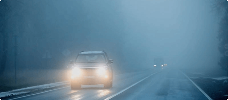 Cars driving on a foggy night.