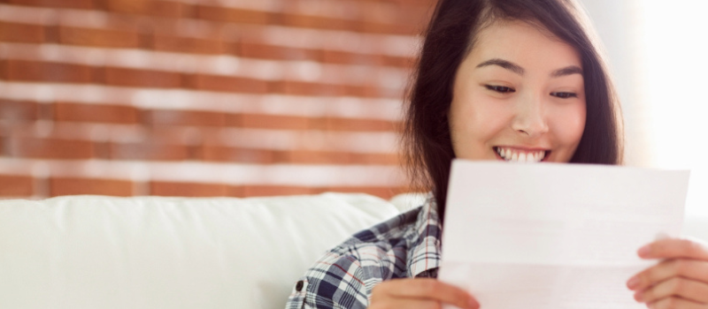 A person smiling as she reads a document.