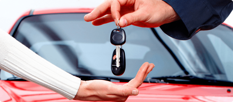 Auto salesperson handing car keys to a buyer. 