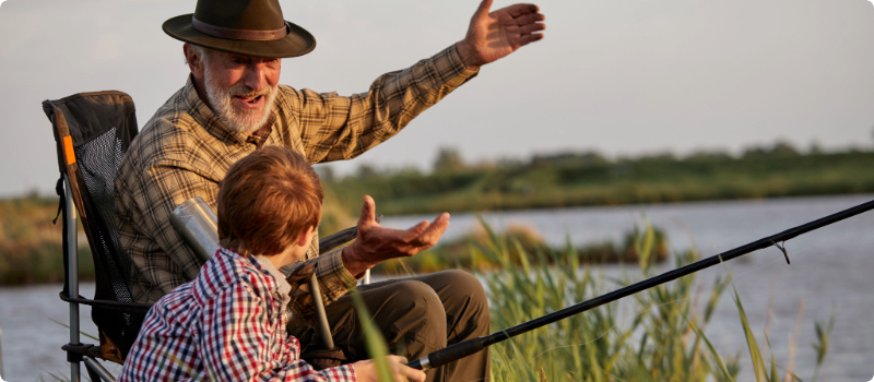 A grandfather fishing with his grandchild.