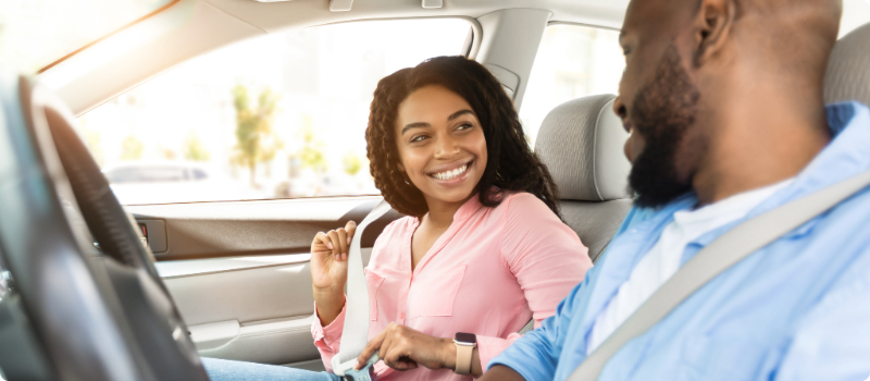 Two people buckling their seatbelts for a drive.