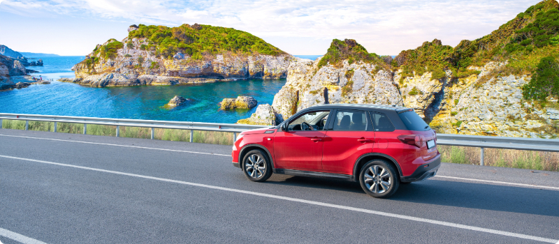 An SUV driving with the ocean in the background.