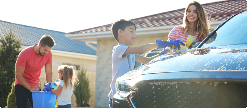 A happy family washing their car on a sunny day.