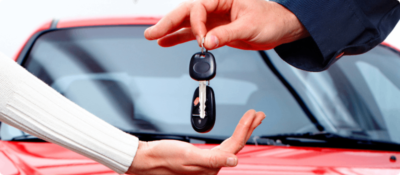 A car salesperson handing car keys to a customer.