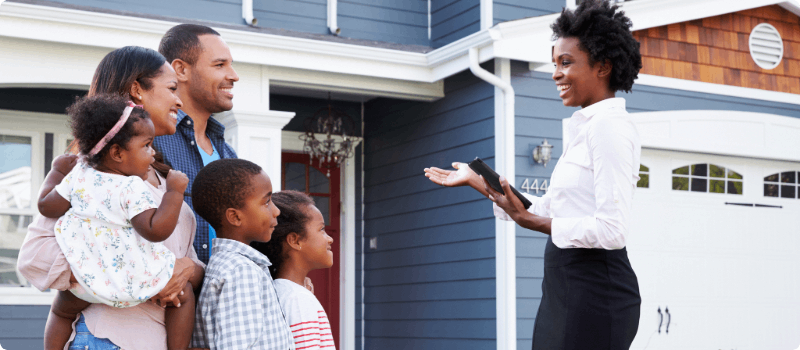 Happy family talking to a realtor while standing in front of a new home.
