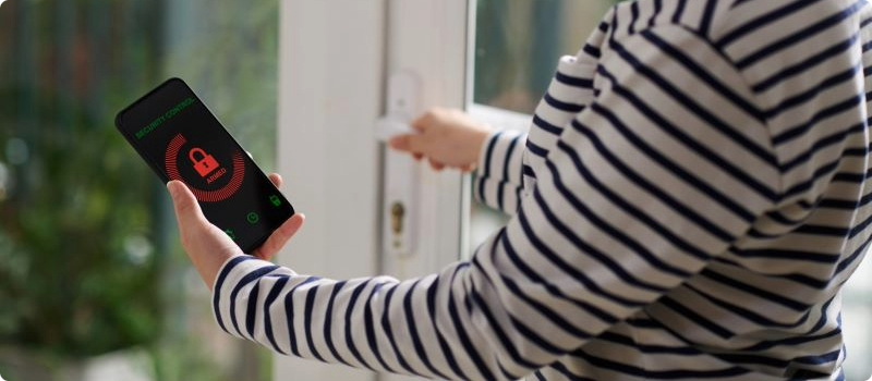 A homeowner using their smart home technology to ensure their home's doors are locked. 