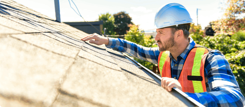 A worker inspecting a home's roof.