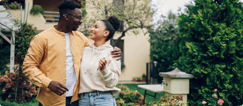 A happy couple standing in front of their new home.