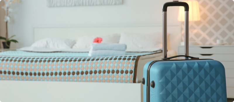 A packed suitcase sitting upright in a hotel room.