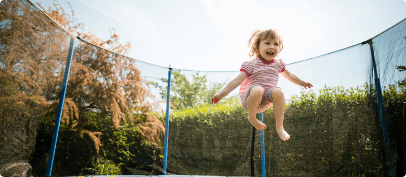 Happy little girl jumping on a trampoline. 