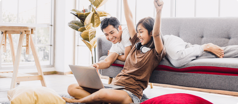Couple celebrating while sitting in front of a laptop.
