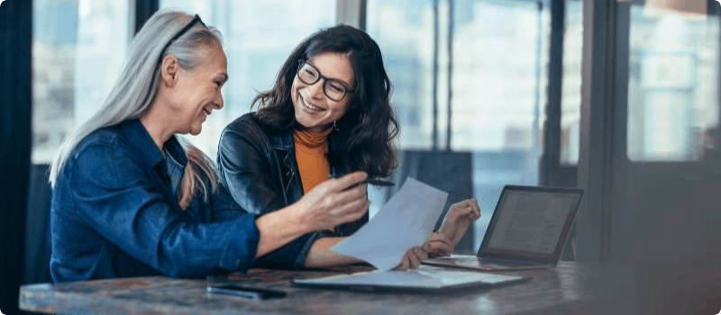 A person reviewing a document with another person while sitting at a desk.