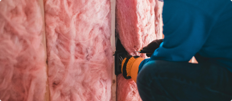 A worker installing fiberglass insulation.