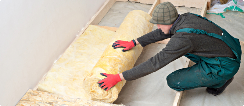 A worker installing mineral wool insulation.