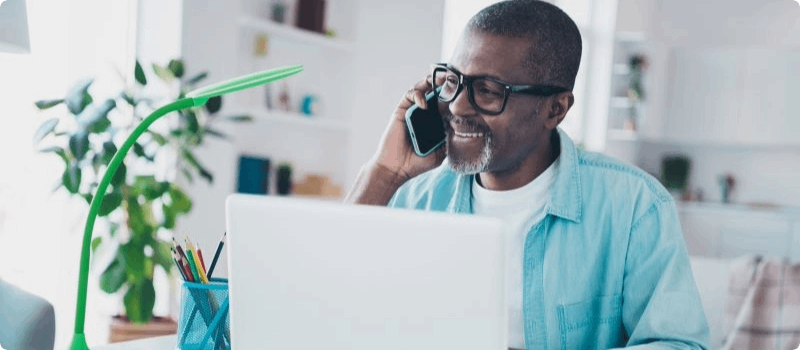 Person talking on the phone in front of a laptop.