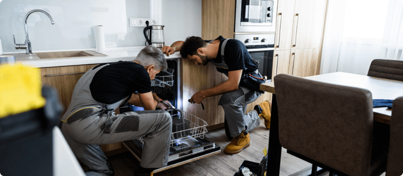 Workers repairing a dishwasher.