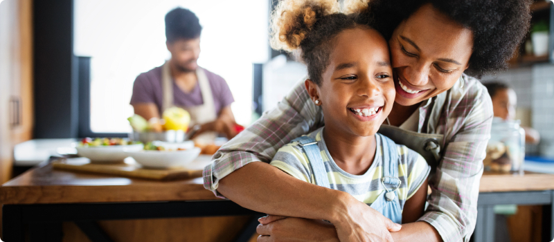 A parent embracing their child in their kitchen.