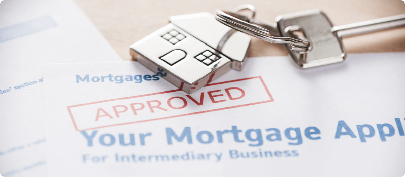A home key resting atop an approved mortgage application.