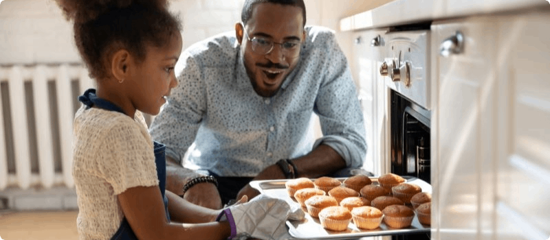 Father and daughter baking muffins together. 