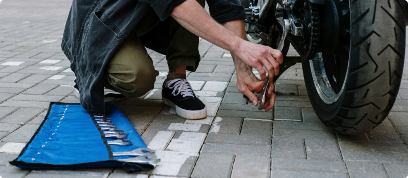 A close-up of a person working on their motorcycle.