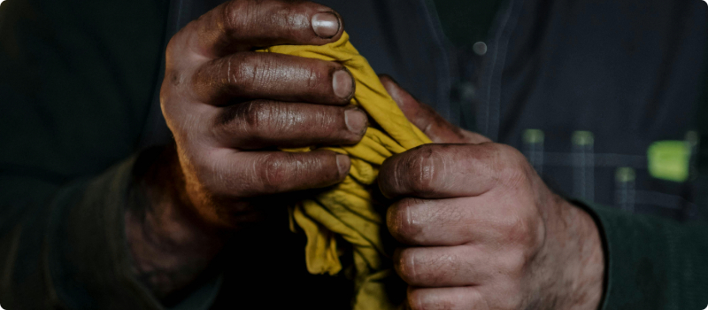 A close-up of a person wiping their oil-covered hands on a shop rag.