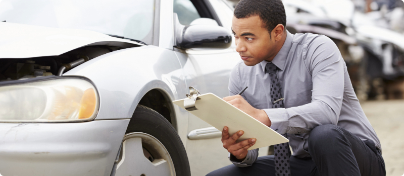 An auto insurance agent documenting accident-related damages on a car.
