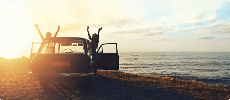 Happy friends parked in front of the ocean. 