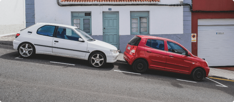 Two cars parked on a downhill slope.