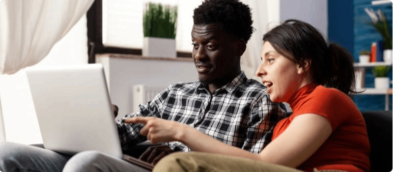 Couple looking at laptop while sitting on a couch. 