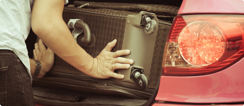 A rideshare driver placing a client's luggage in a trunk.