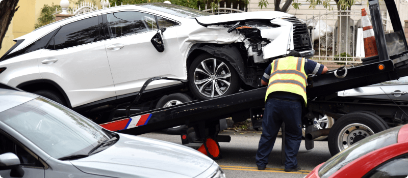A tow truck driver loading a vehicle onto his truck.