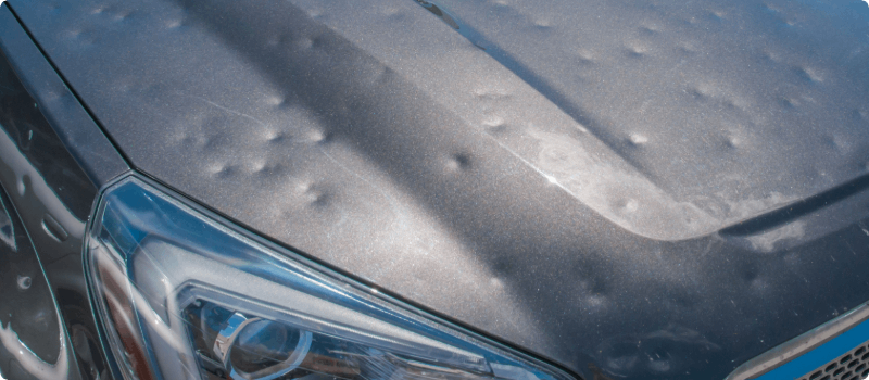 A close-up of a hail-damaged car.