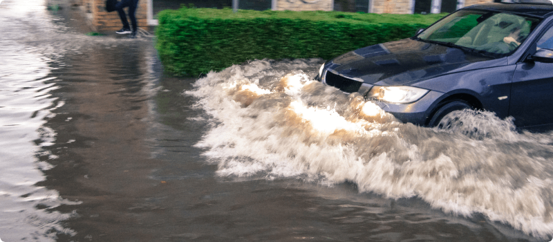 A close-up of a vehicle driving through floodwaters.