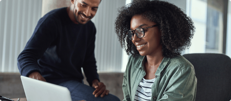 A smiling couple looking at a laptop.