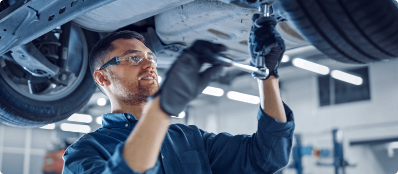 A mechanic working under a vehicle in a shop.