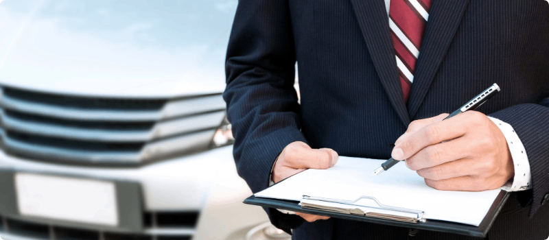 Salesperson at car dealership reviewing a document. 