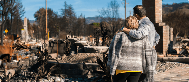 Couple looking at their leveled home after a tornado.